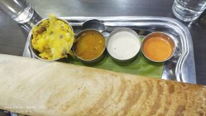 A dish of crispy Rava dosa accompanied with chutney and sambar.